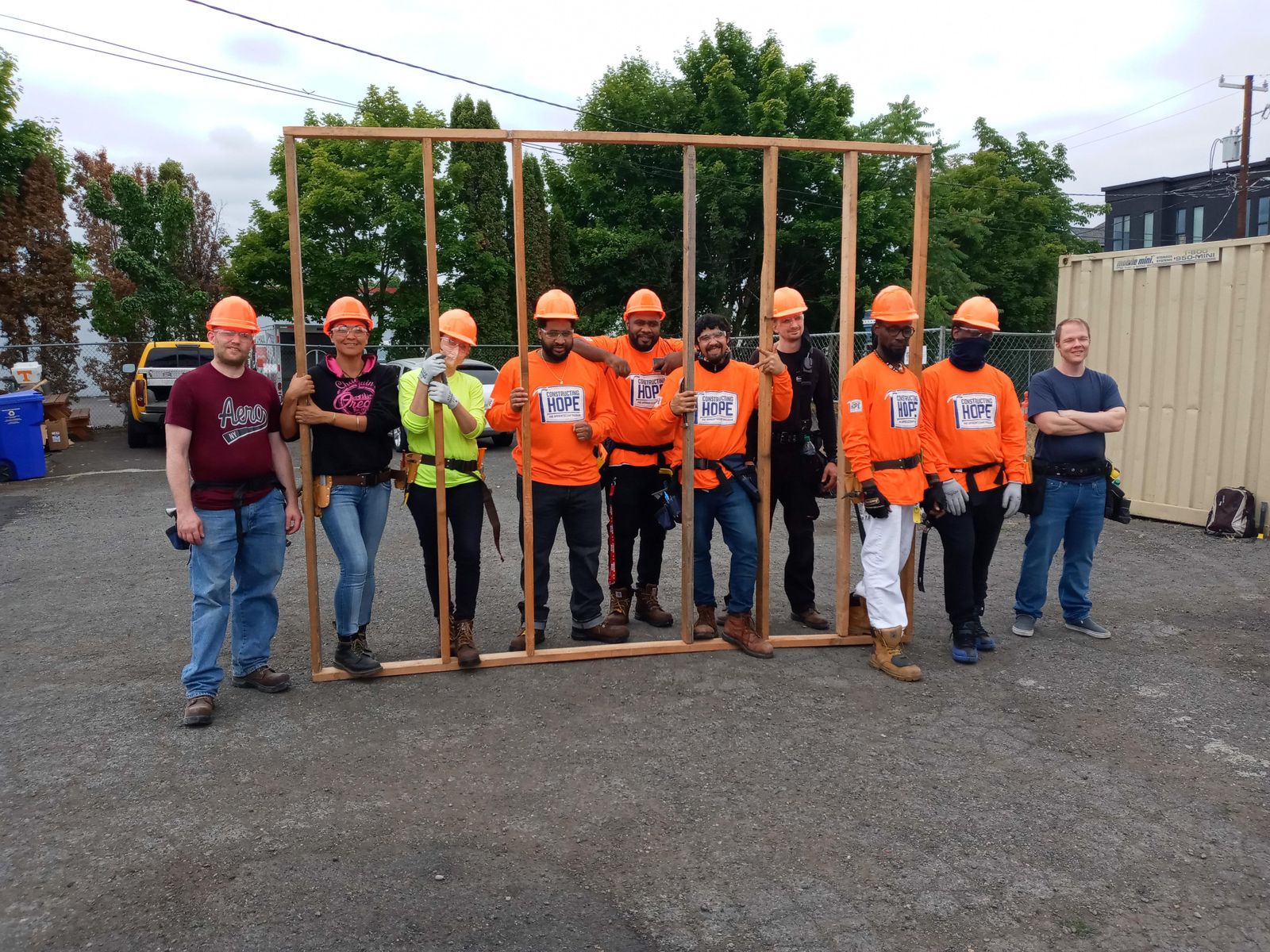 Several construction workers hold up a recently built wall structure.