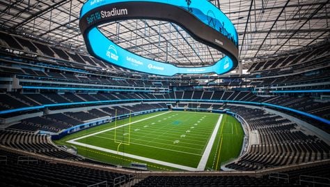 Interior of football stadium with large, ring-shaped video board.